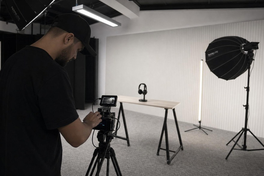Operator de imagine reglând camera pe platoul de filmare, cu masa de produs și luminile pregătite.